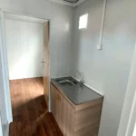 Office container interior featuring a practical kitchenette and direct access to adjacent workspaces.