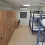 Construction accommodation container equipped with bunk beds, wardrobes and climate control for worker housing.
